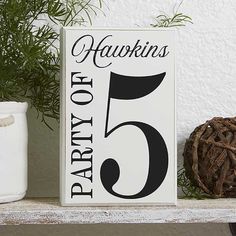 a wooden sign sitting on top of a white shelf next to a potted plant