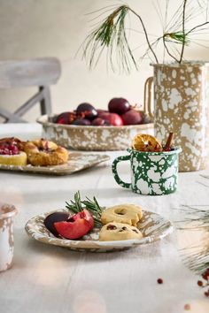 two plates with pastries on them sitting on a table next to cups and mugs