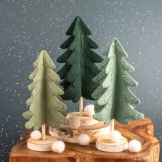 three wooden trees on a table with snow falling around them