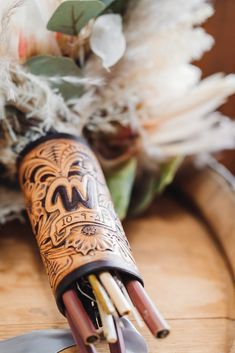 a knife and some flowers on a wooden table in a vase with feathers around it