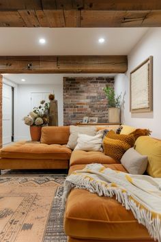 a living room filled with lots of furniture next to a brick wall and wooden beams