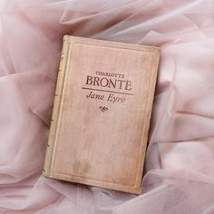 a book laying on top of a bed covered in pink fabric