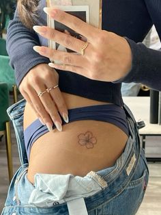 a woman is showing off her stomach with a flower tattoo on it's side