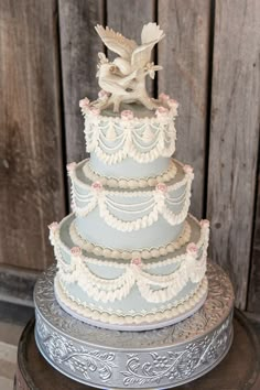 a three tiered wedding cake sitting on top of a wooden table next to a wall