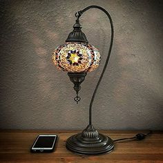 a lamp that is sitting on top of a wooden table next to a cell phone