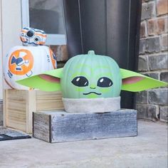 two star wars pumpkins sitting on top of a wooden box