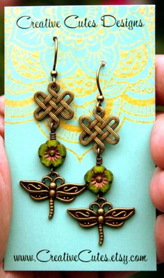 Rustic bronze dragonflies sway from earthy green glass flowers & bronze Celtic knots...Outlander Inspired! Uniquely hand crafted with these quality materials: ~ Czech glass flower beads with a gold Picasso finish ~ Antiqued Brass dragonfly and Celtic knot charms ~ Antiqued brass lead & nickel-free French hook style ear wires ~ Silicone earring backs to keep earrings securely in ears Measuring 2~1/4 inches from the top of the ear wires to the bottom of the charms, they're comfortably ligh Bohemian Wire Wrapped Flower Earrings, Artistic Green Flower-shaped Jewelry, Handmade Green Dragonfly Jewelry, Bohemian Bronze Flower Earrings Nickel-free, Bohemian Bronze Flower Earrings Nickel Free, Bohemian Wire-wrapped Flower Earrings, Bohemian Wire Wrapped Flower Earrings For Gift, Bohemian Wire Wrapped Flower Earrings As Gift, Green Adjustable Dangle Flower Earrings