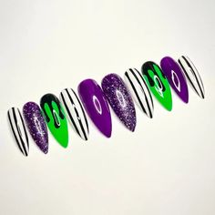 Unleash your spooky spirit with our Beetlejuice Halloween press-on nails in purple, green, and black glitter. These striking fingernails offer a perfect blend of eerie elegance and durability. Ideal for those seeking trendy, reusable nail enhancements that make a bold statement this Halloween.📦 What comes with your press on nail kit? 10 nails of your size 24 adhesive tabs 1 nail file 1 cuticle stick Instructions on how to apply and remove them. Finding Your Size:Check out our sizing chart or Vi Acrylic Nail Designs Trendy, Neon Nails Halloween, Horror Nails Simple, Purple And Green Nail Ideas, Halloween Pointy Nail Designs, Beetlejuice Acrylic Nails, Emerald Green Halloween Nails, Green And Purple Nails Ideas