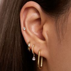 a woman wearing three different types of ear piercings on her left ear and the other one has a diamond in it