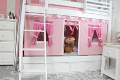 a child's bedroom with bunk beds and pink curtains