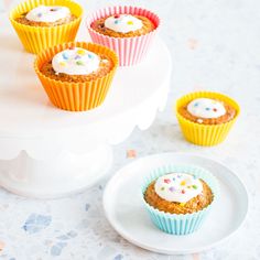 small cupcakes with white frosting and sprinkles are on a cake stand