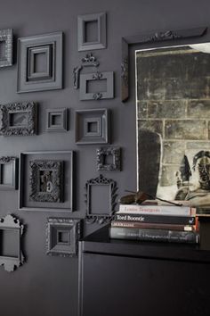 a black wall with many frames and pictures on it