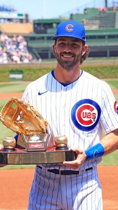 a baseball player holding a trophy on top of a field