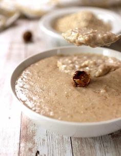 a bowl of oatmeal is being spooned into the bowl with some oats in it