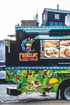 a colorful food truck parked on the side of the road in front of a building