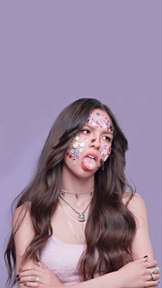 a woman with her face painted in different colors and makeup looks like she is holding her hands on her chest