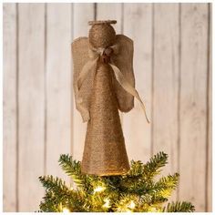 an angel ornament on top of a christmas tree with lights around the base