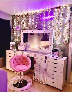 a desk with a mirror, pink chair and christmas lights