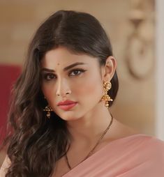 a woman in a pink sari and gold earrings