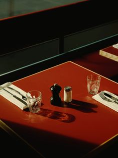 a red table topped with glasses and silverware