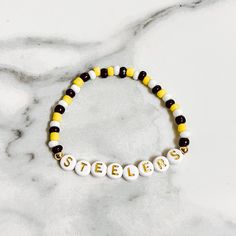 a yellow and white beaded bracelet with the word spelled out in letters on it