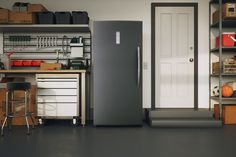 a refrigerator in the middle of a garage with shelves and drawers on either side of it