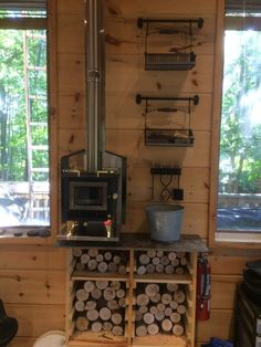 a stove top oven sitting on top of a wooden shelf next to a firewood rack