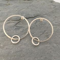 Silver hoop earrings, hammered hoop earrings, large hoop earrings These contemporary earrings are made from sterling silver that has been hammered to give texture and shine. You can choose from two finishes, flat brushed satin finish or a hammered sparkly finish.  The large hoop fastens to the ear with a traditional post and butterfly fitting. The small hoop hangs freely from the large one so it moves easily and catches the light. The large hoop has a diameter of approximately 2.5cm and the smal Modern Hammered Open Circle Earrings, Hoop Earrings Large, Large Silver Hoop Earrings, Stick Earrings, Hammered Hoop Earrings, Contemporary Earrings, Heart Hoop Earrings, Earrings Large, Large Hoop Earrings