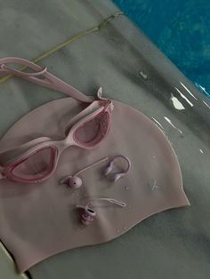 a pair of pink swimming goggles sitting on top of a towel next to a pool