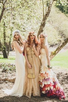 three women in dresses standing next to each other under a tree with flowers on them