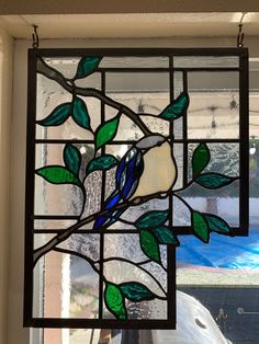 a stained glass window with green leaves and blue bird on it's back side