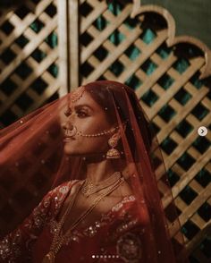 a woman wearing a veil and jewelry standing in front of a wall