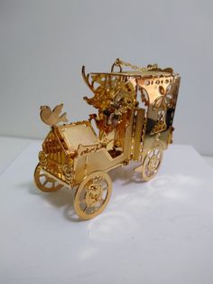 a golden carriage with an animal on the back and gold decorations in the front, sitting on a white surface