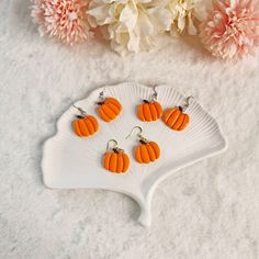 four small pumpkins are sitting on a white plate next to some pink and white flowers