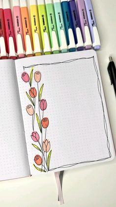 an open notebook with markers and flowers on it