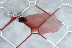 a glass filled with red liquid sitting on top of a tiled floor