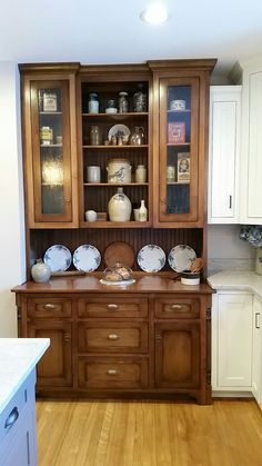 a kitchen with wooden cabinets and white cupboards on top of each other in front of an island