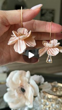 a person holding two flower shaped earrings in their left hand and another one on the right