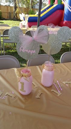 two pink mason jars with minnie mouse ears on them sitting on top of a table