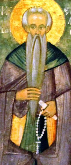 an icon with a bearded man wearing a green robe and holding a white cross in his right hand