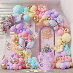 a pink and blue balloon arch with butterflies on it, surrounded by balloons in pastel colors