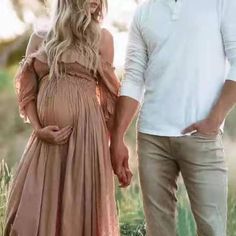 a man and woman holding hands while standing next to each other in a grassy field