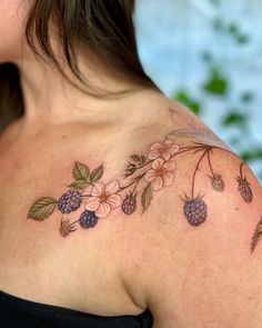 a woman's shoulder with flowers and berries on it