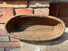 a wicker basket sitting on top of a stone wall next to a brick building