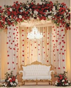 a white couch sitting under a chandelier covered in red and white flowers