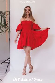 a woman in a red dress posing for the camera with her hands on her hips