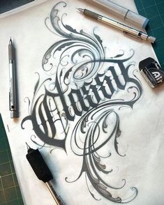 some type of calligraphy that is on top of a piece of paper with pens