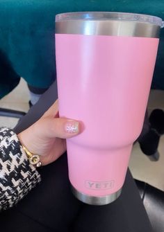 a woman's hand holding a pink yeti cup