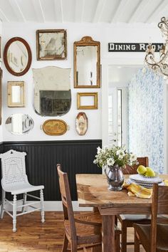 a dining room table with chairs and pictures on the wall above it in front of a mirror