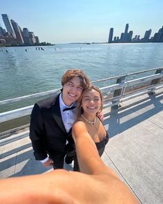 a man and woman taking a selfie in front of the water